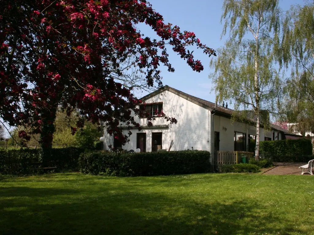 Een van de woningen in het voorjaar, met een bloeiende boom op het gazon